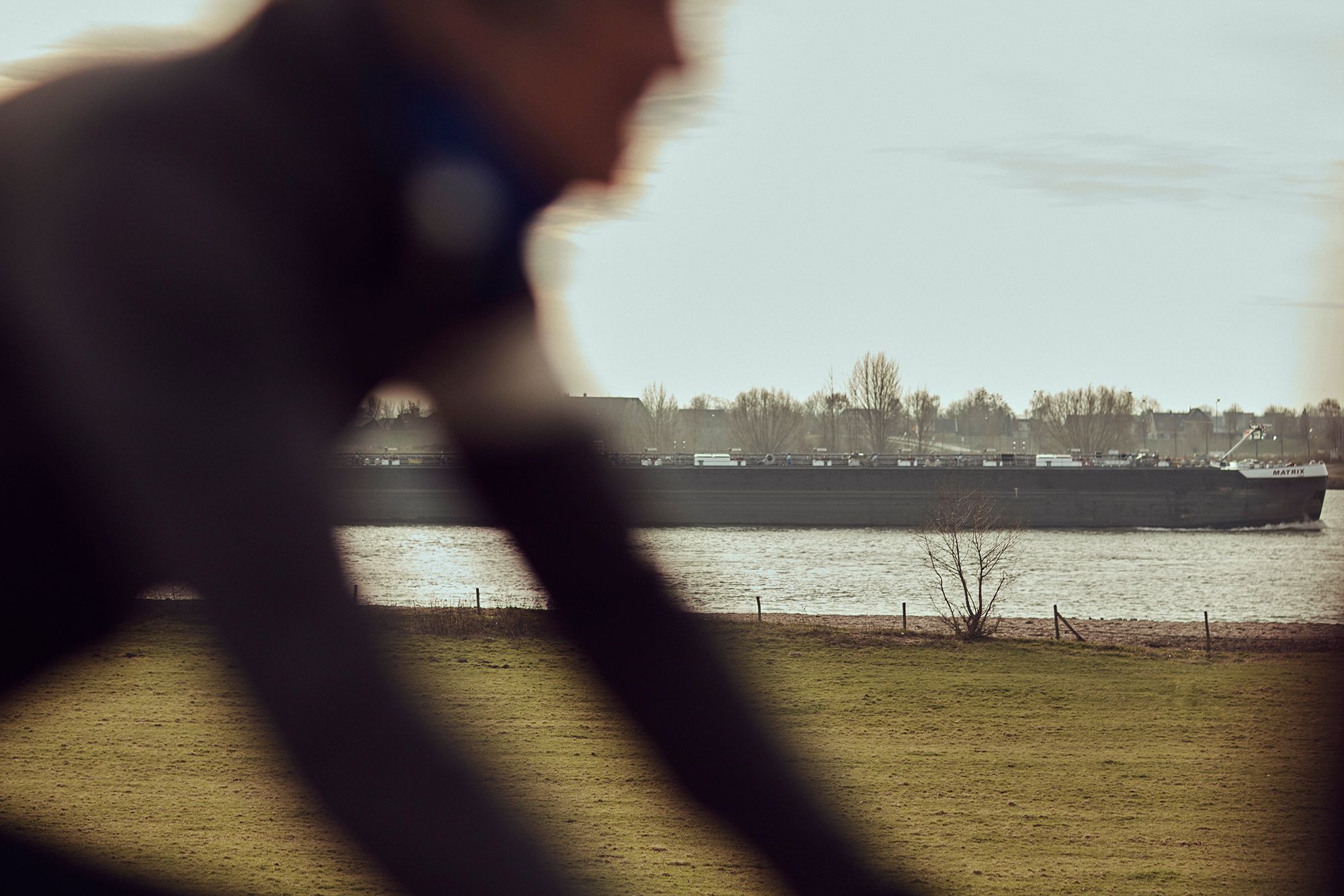 A blurred close view of Albert riding beside the river