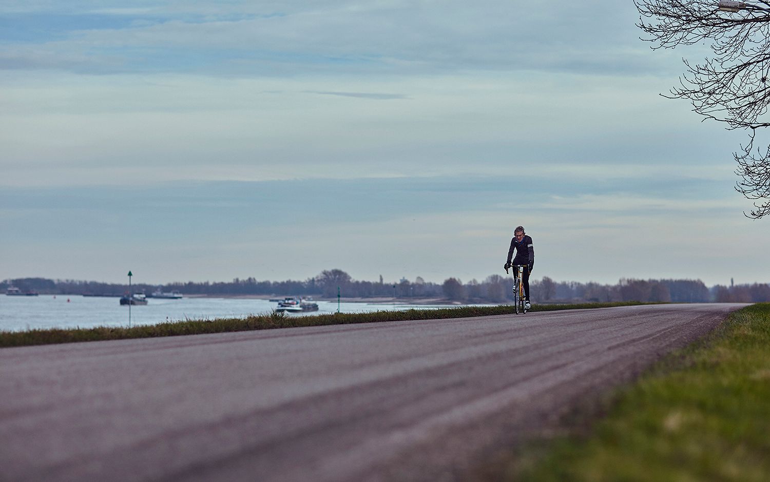 Albert riding on a dike road beside the river