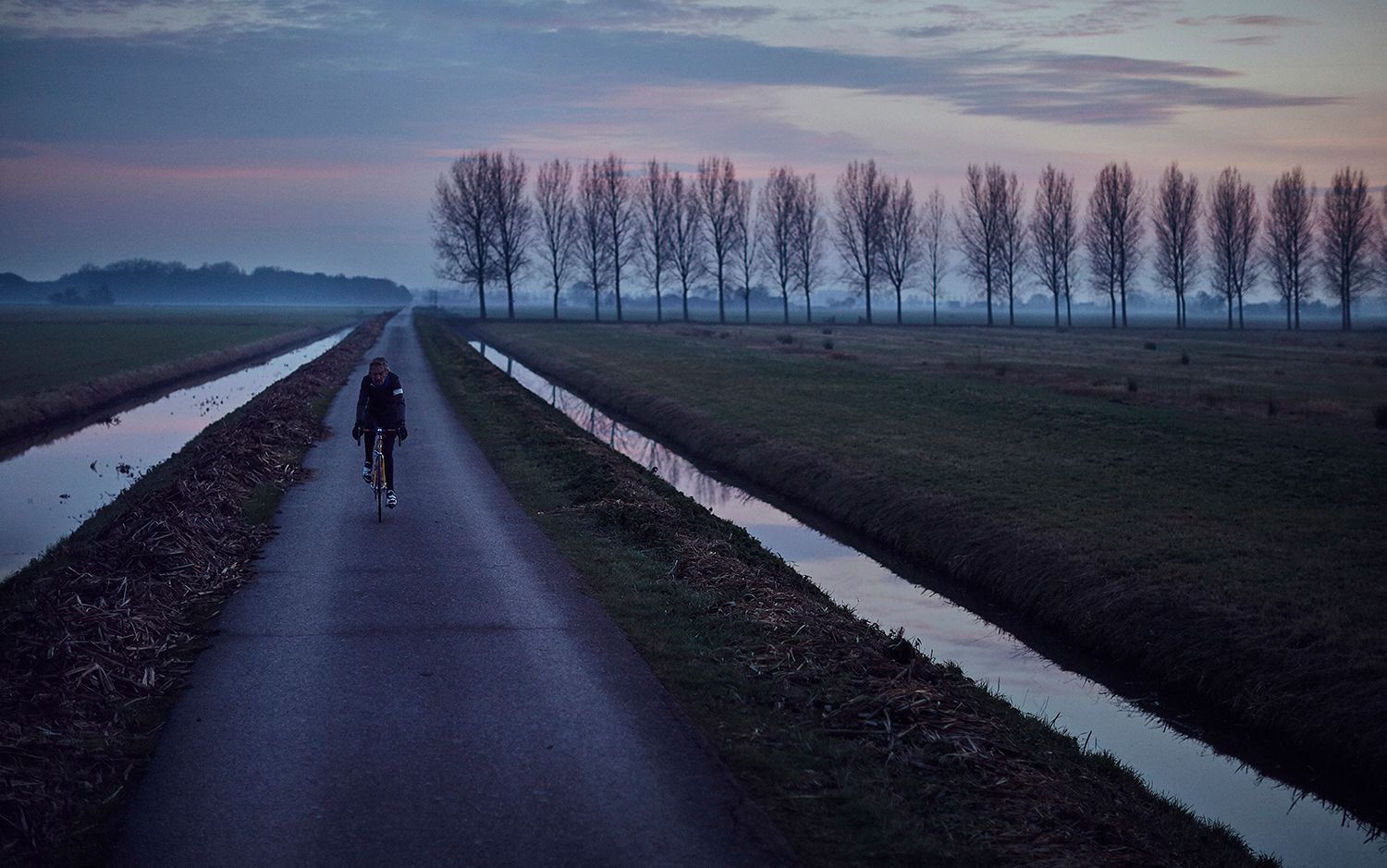 Albert riding between drainage ditches at dusk
