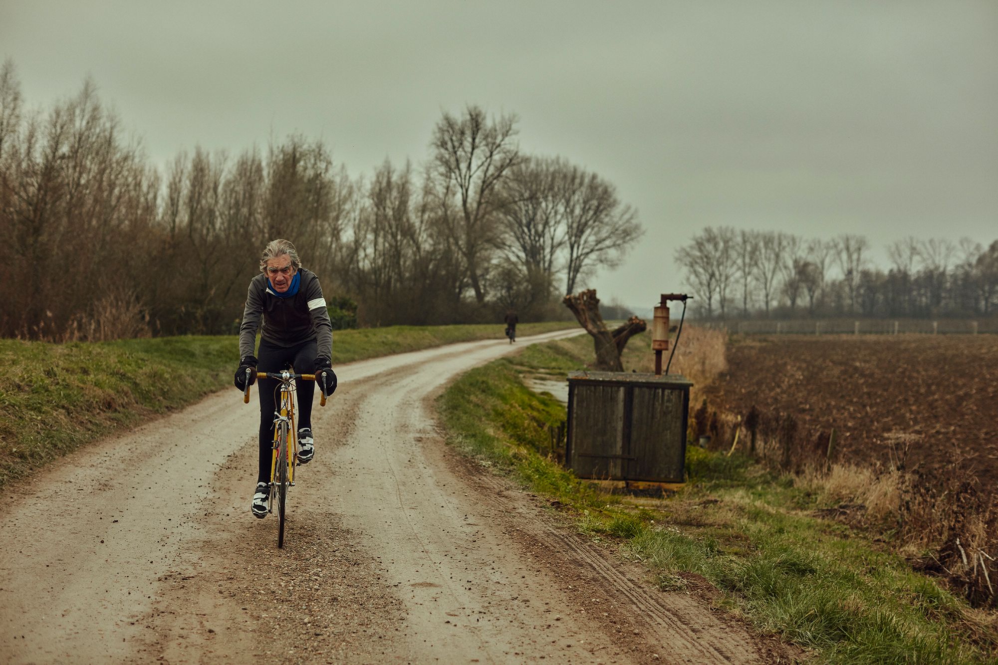 Albert riding along a gravel road through flat farmland