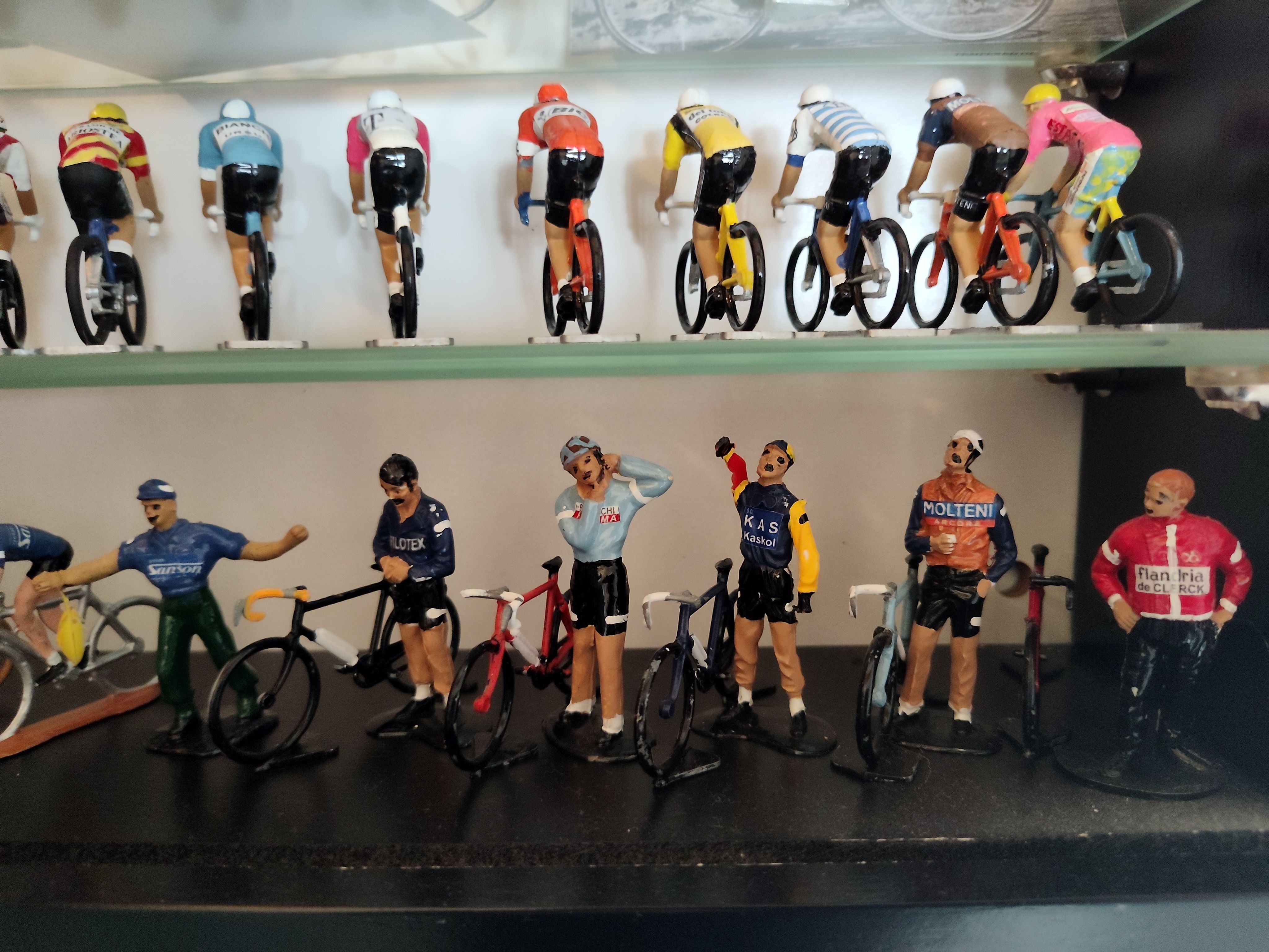 Collection of miniature cyclists displayed in a cabinet