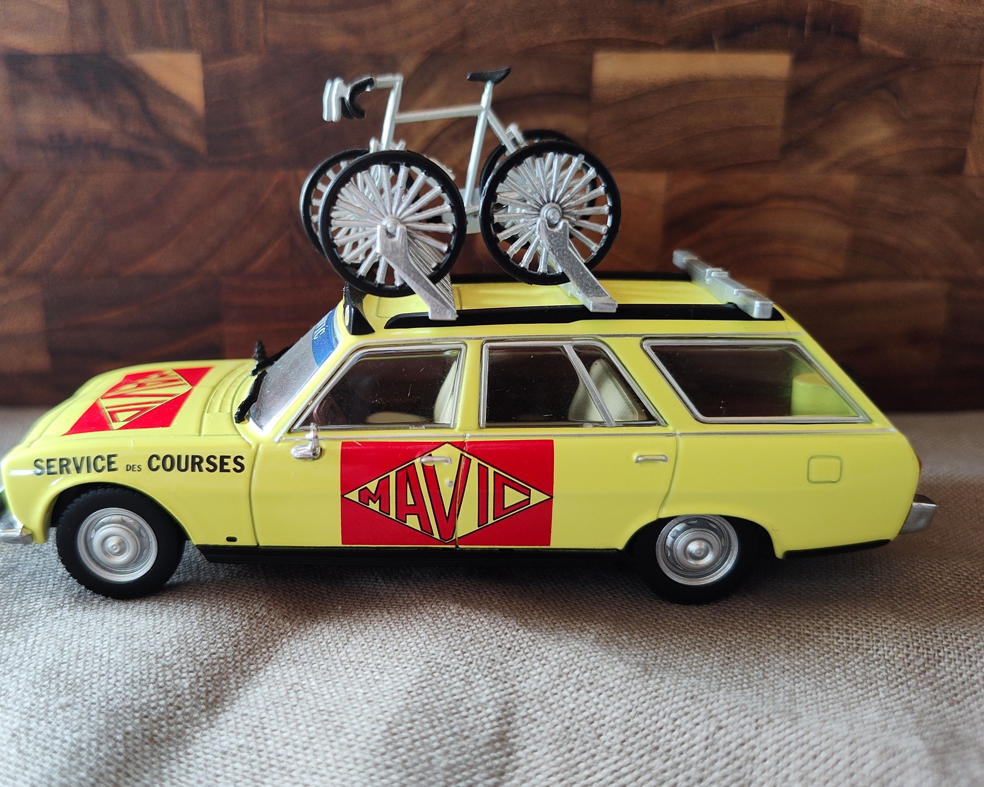 Yellow Mavic miniature service car with a bicycle on its roof
