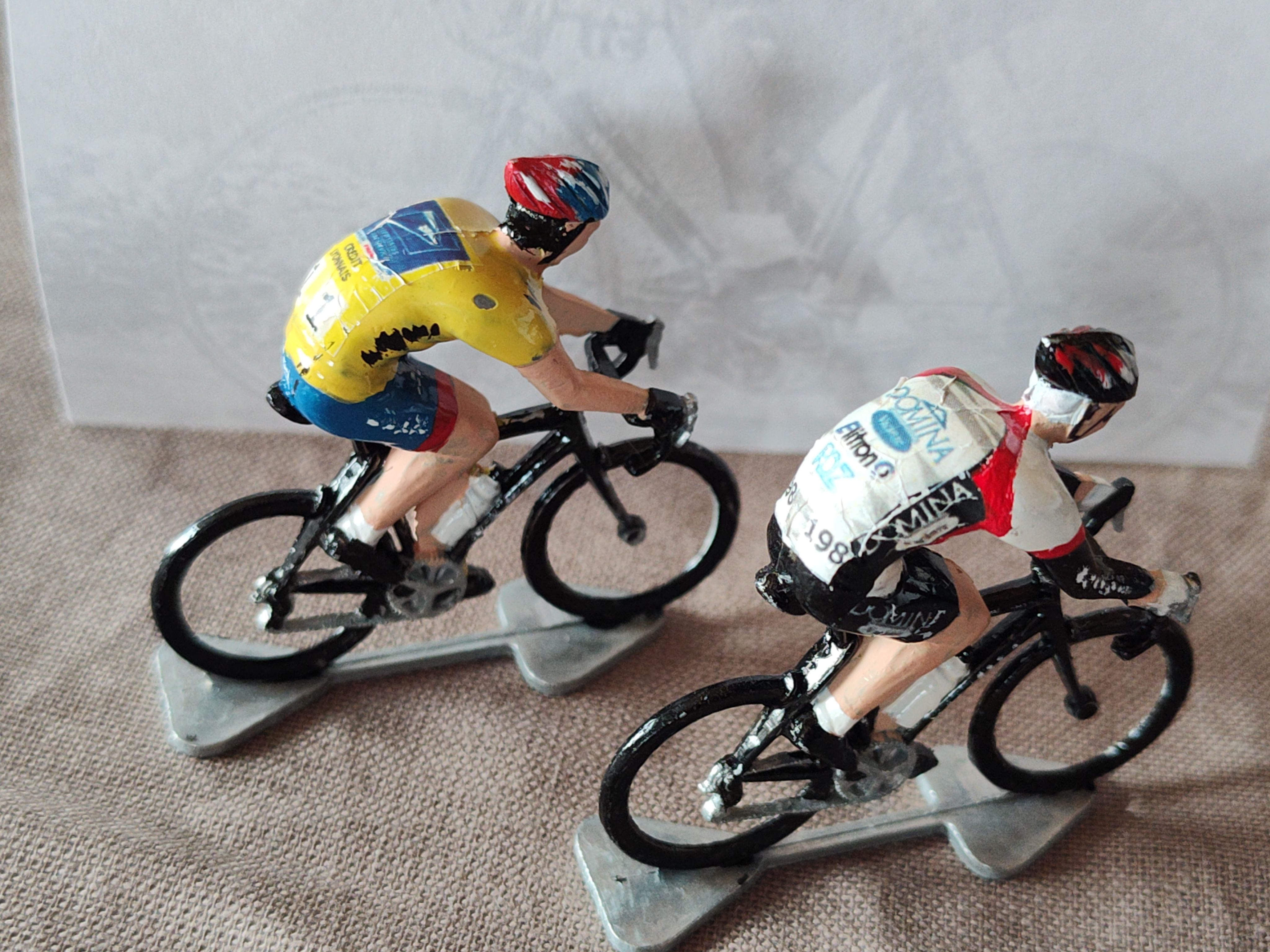 Two later miniature cyclists in team jerseys