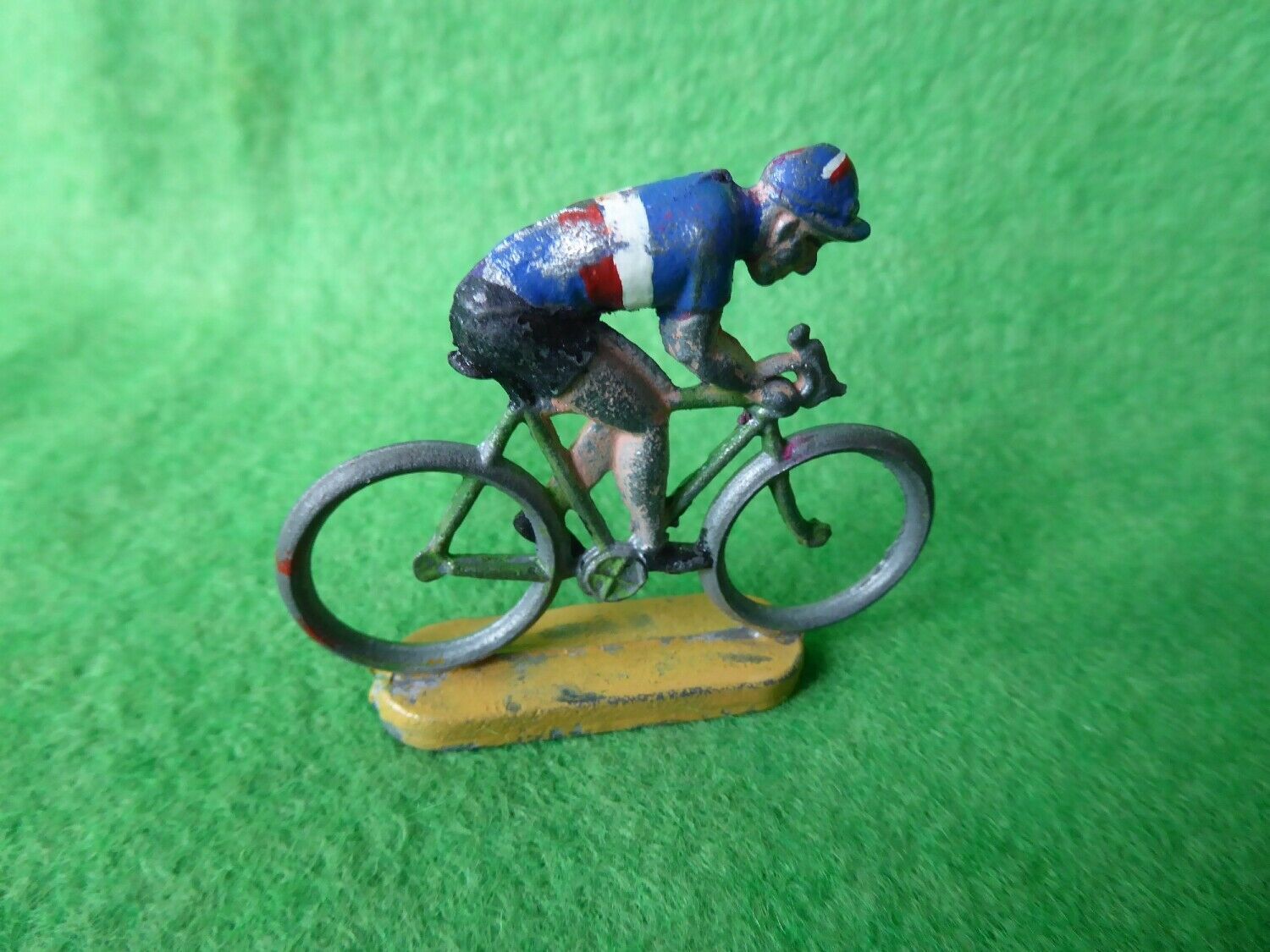 Heavily worn older miniature cyclist in a blue, white and red jersey