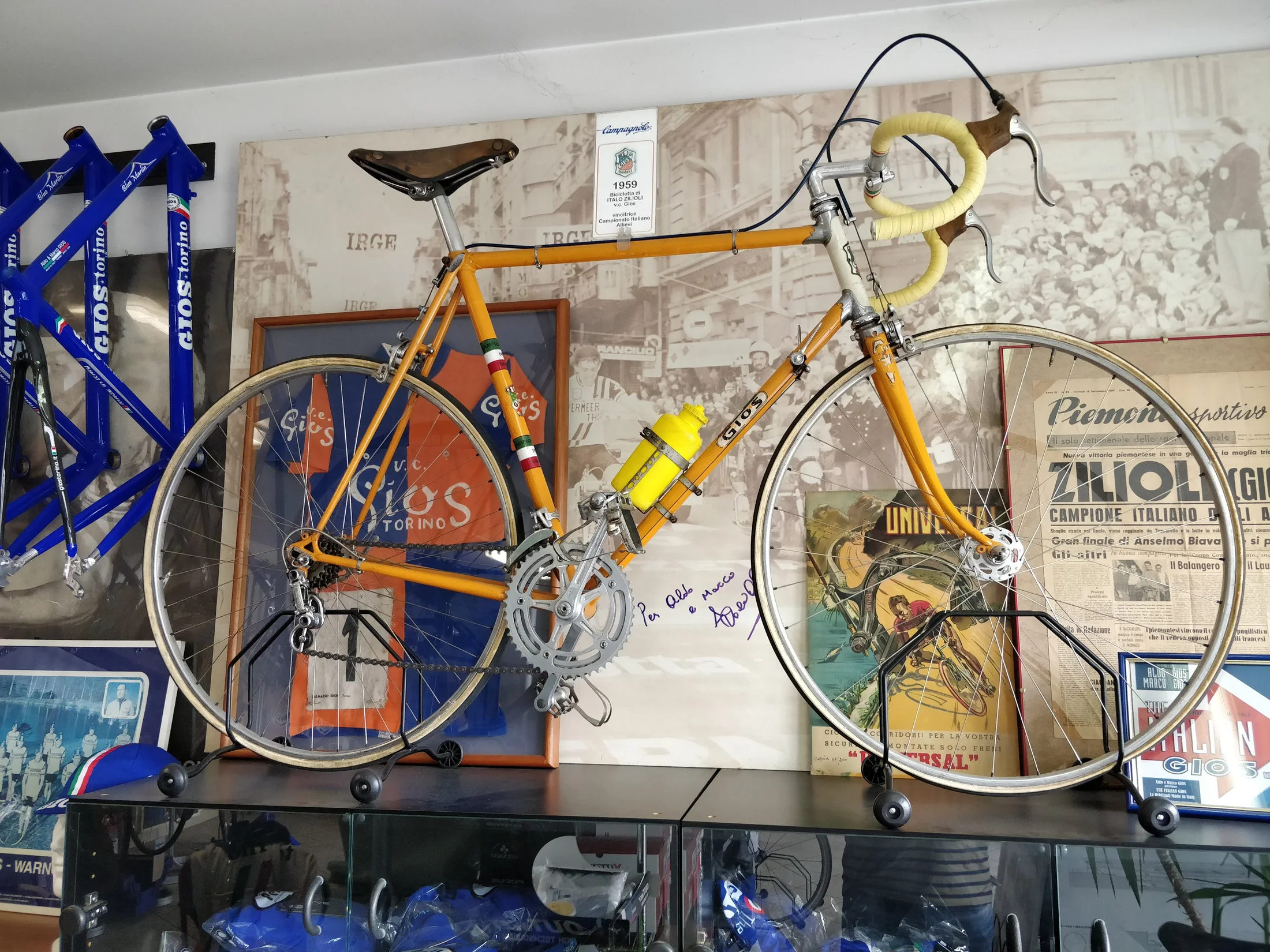 Ældre orange GIOS-racercykel udstillet blandt fotografier og memorabilia i Torino