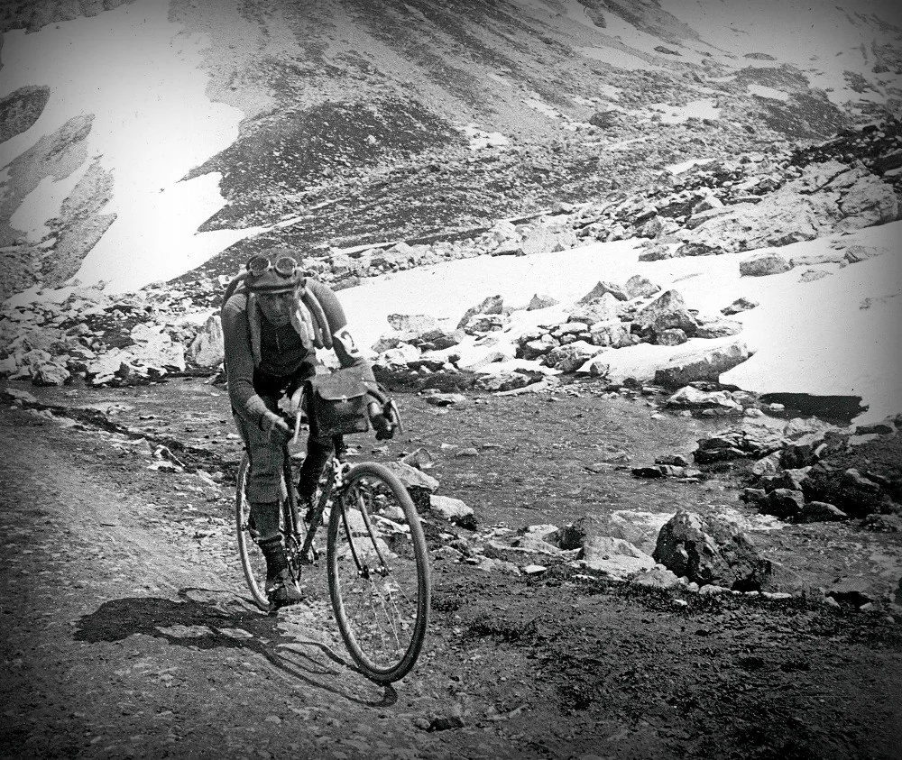 Rider with spare tyres on a rough road in snow-covered mountains