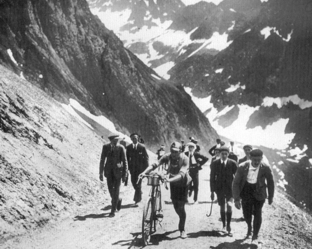 Rider pushing his bicycle on a snow-covered mountain pass